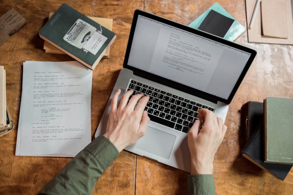 copywriter che scrive al computer con fogli e libri su una scrivania
